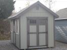 Pine Creek 8x12 Cape Cod with PC Green walls, Chestnut trim and Navajo White Z-Style shutters, and Brown metal roof